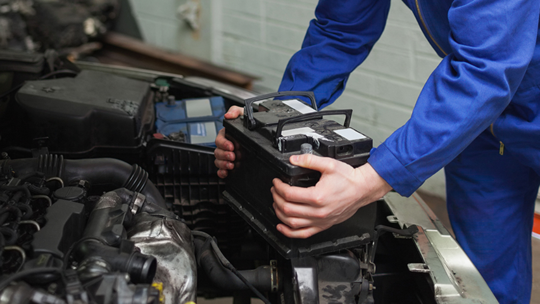 Male mechanic checking car battery in workshop