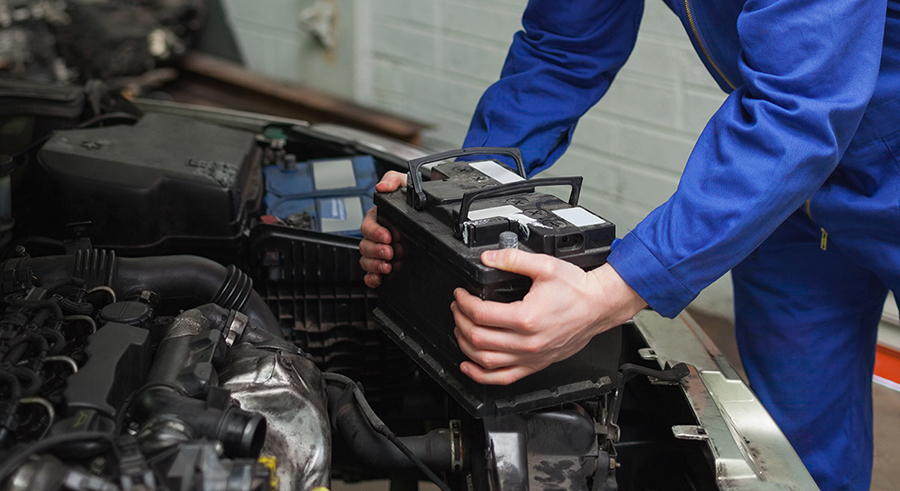 Male mechanic checking car battery in workshop